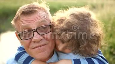 可爱的卷曲孙子拥抱他的祖父。 一个戴眼镜的养老金<strong>领取</strong>者和他的孙子在河边上学